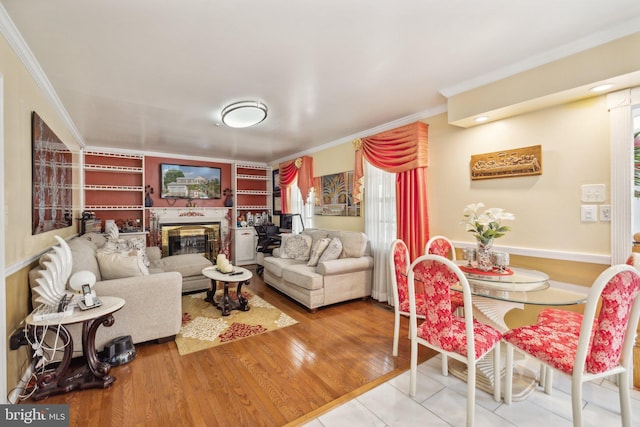 living area featuring crown molding, a glass covered fireplace, and wood finished floors