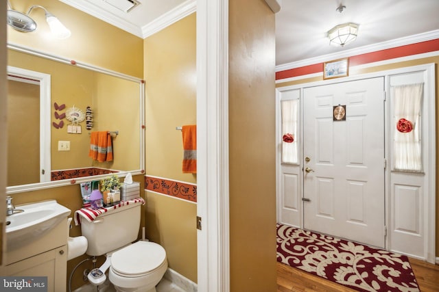 foyer entrance featuring visible vents, crown molding, and wood finished floors