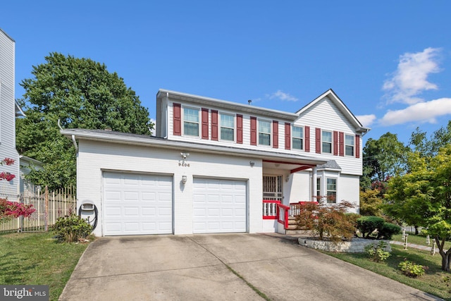 traditional-style house with a porch, concrete driveway, fence, and brick siding