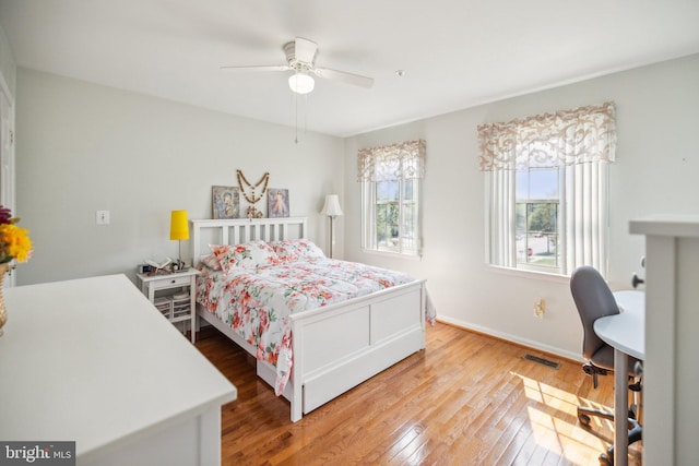 bedroom with light wood-style floors, visible vents, baseboards, and ceiling fan