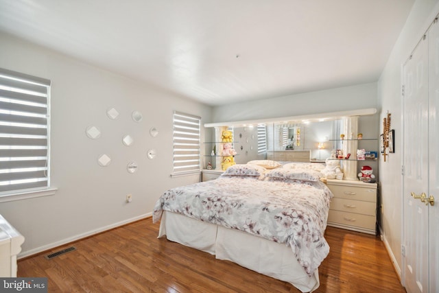 bedroom featuring wood finished floors, visible vents, and baseboards