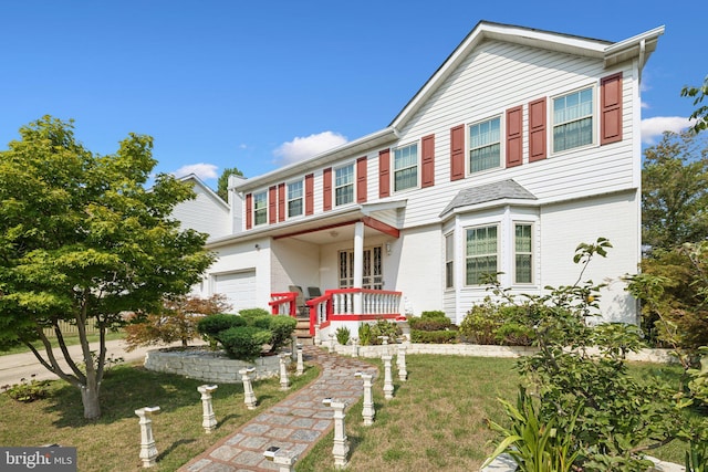 traditional-style home featuring a front yard, brick siding, and a garage