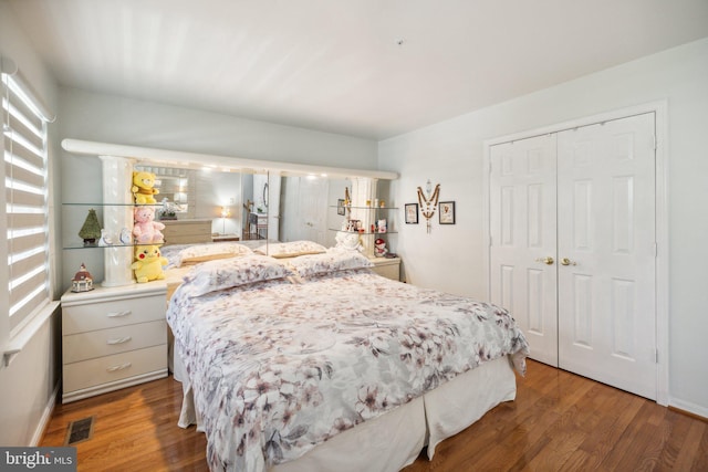 bedroom featuring a closet, visible vents, wood finished floors, and baseboards