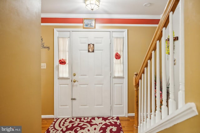 foyer featuring crown molding, wood finished floors, and baseboards