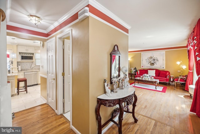 hallway featuring light wood finished floors and ornamental molding