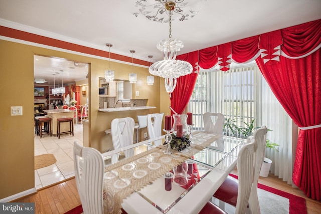 dining area featuring a fireplace, a healthy amount of sunlight, an inviting chandelier, and crown molding