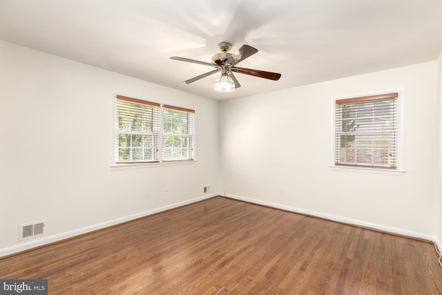 spare room with baseboards, wood finished floors, and a ceiling fan