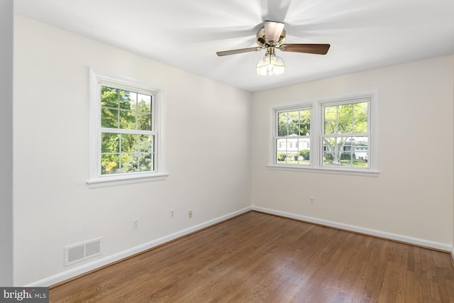 spare room featuring baseboards, wood finished floors, and ceiling fan