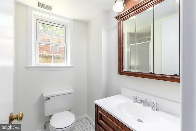 bathroom featuring baseboards, toilet, vanity, and a shower with shower door
