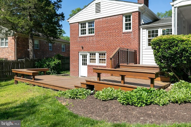 back of house featuring a chimney, brick siding, and a wooden deck