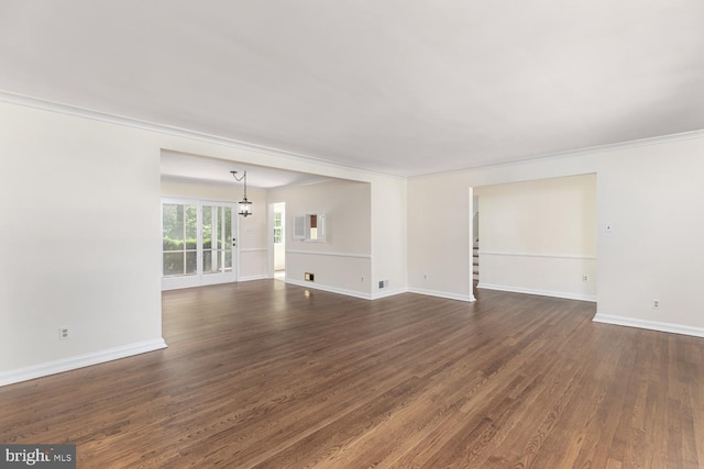 unfurnished living room with dark wood finished floors, baseboards, ornamental molding, and a chandelier