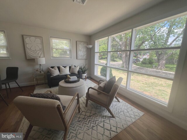 living area with baseboards, visible vents, and wood finished floors