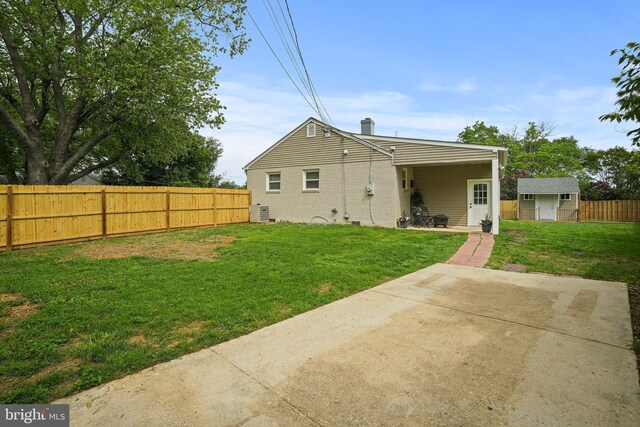 back of house featuring a patio area, a storage shed, a chimney, an outbuilding, and brick siding