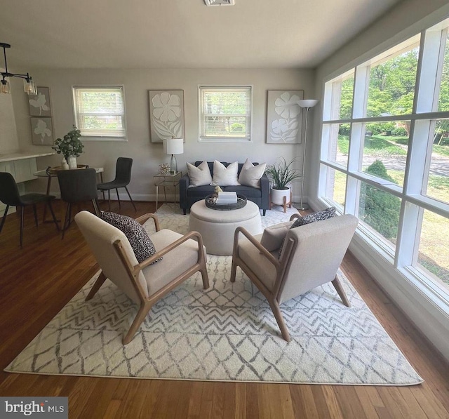 living area with visible vents, wood finished floors, and baseboards