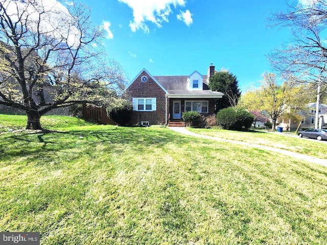 cape cod home featuring fence, brick siding, a chimney, and a front yard