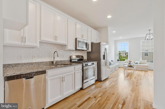 42248 Lancaster Woods Sq, Chantilly, VA 20152 - kitchen with stainless steel appliances, a sink, white cabinetry, light wood finished floors, and light stone countertops