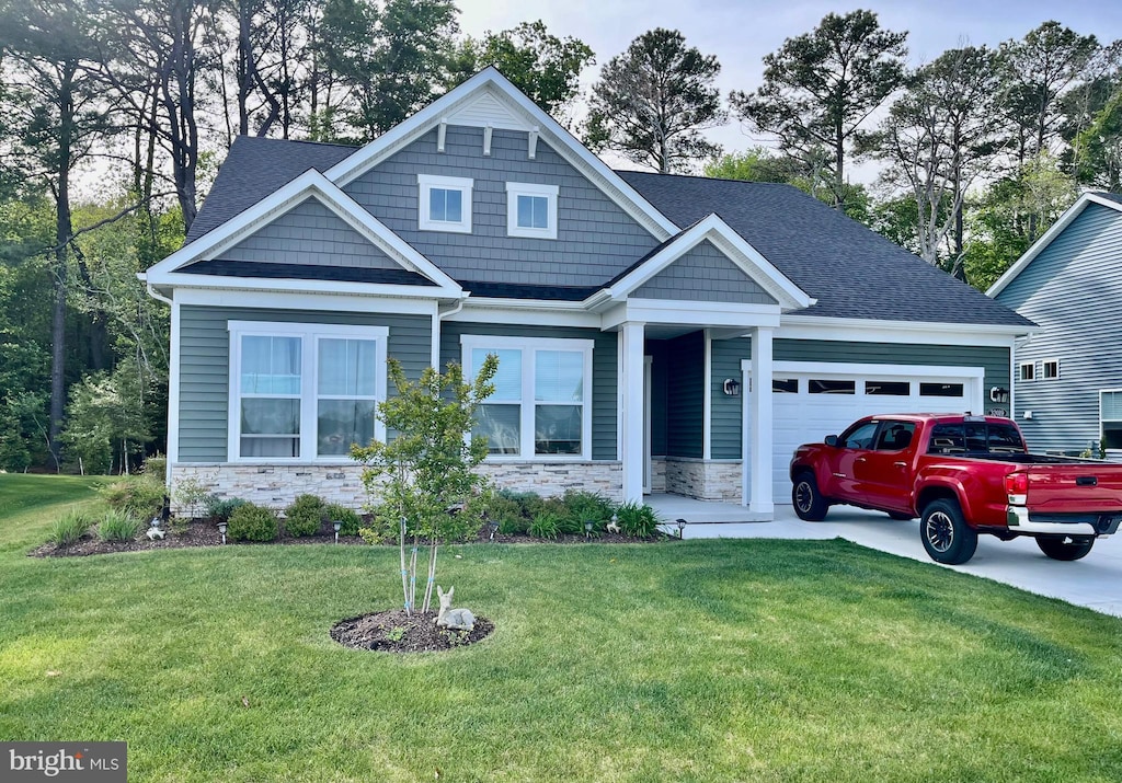 craftsman house with a front lawn, stone siding, a shingled roof, and a garage