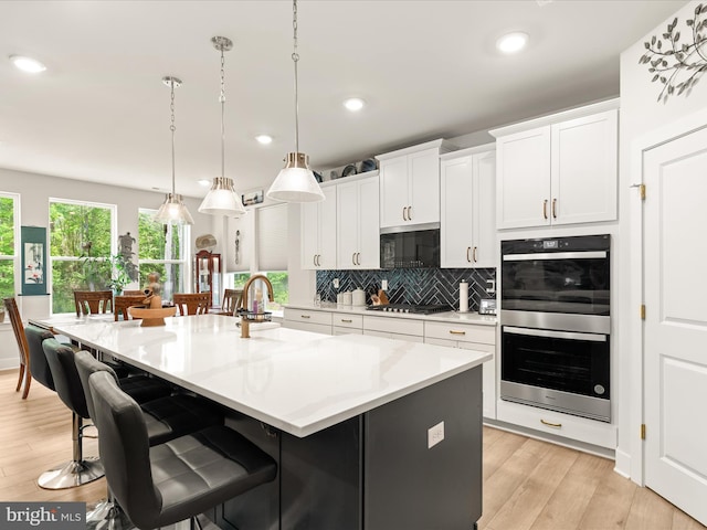 32019 Carlisle Ct, Frankford, DE 19945 - kitchen with stainless steel appliances, light wood finished floors, tasteful backsplash, white cabinetry, and a large island