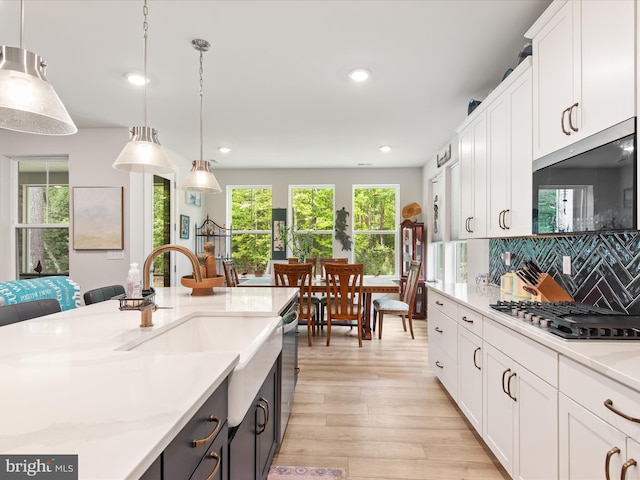 32019 Carlisle Ct, Frankford, DE 19945 - kitchen featuring stainless steel appliances, light wood-type flooring, hanging light fixtures, white cabinetry, and backsplash