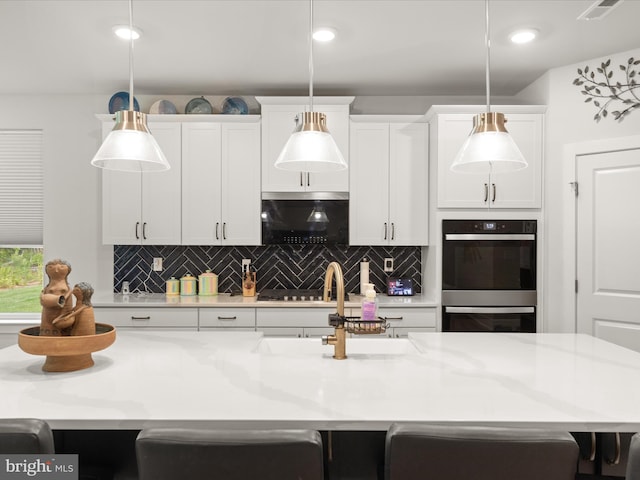 32019 Carlisle Ct, Frankford, DE 19945 - kitchen featuring decorative backsplash, white cabinets, a sink, a kitchen bar, and decorative light fixtures