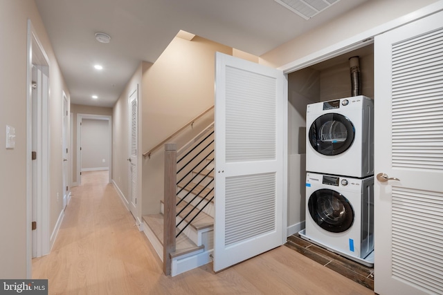 laundry room with stacked washer and dryer, visible vents, laundry area, and light wood-type flooring