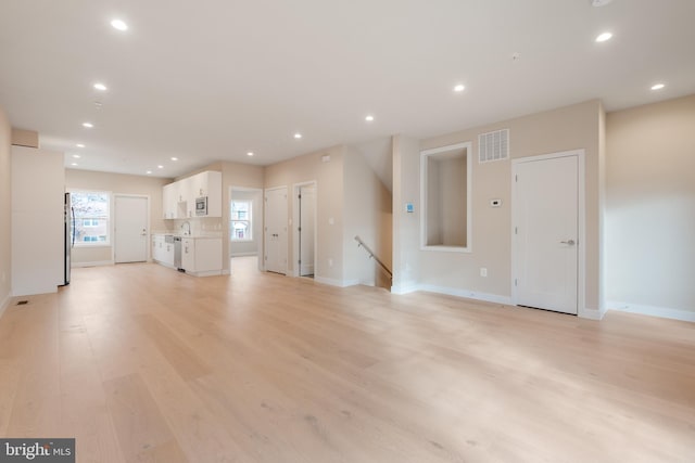 unfurnished living room with recessed lighting, baseboards, light wood finished floors, visible vents, and a sink