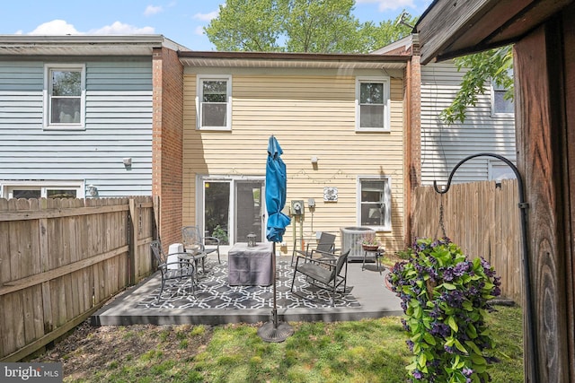 rear view of house featuring a fenced backyard, a patio area, and central air condition unit
