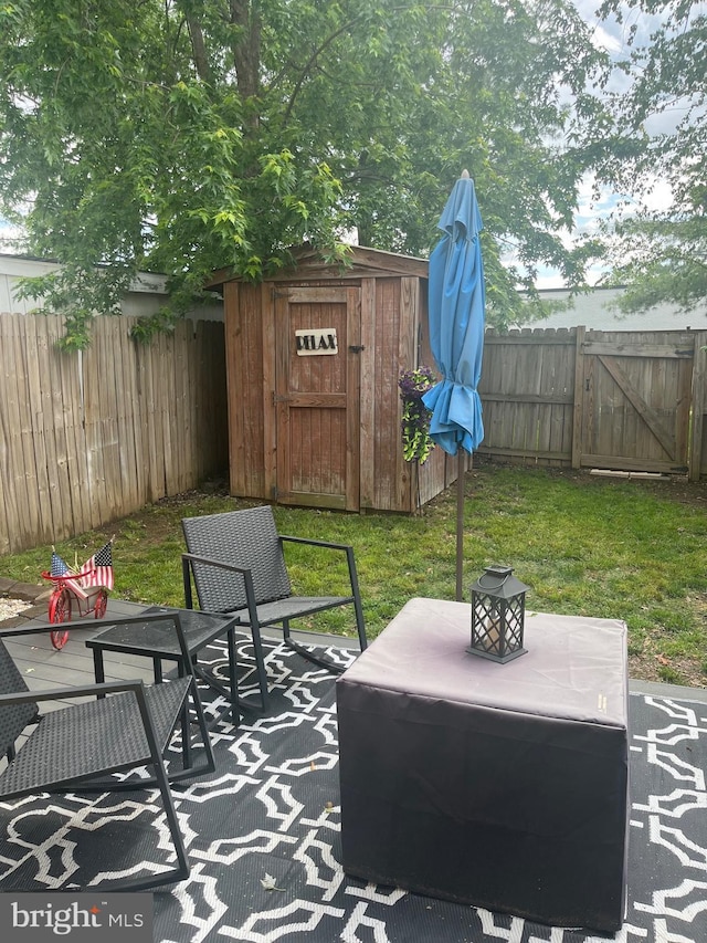 view of patio / terrace with an outdoor structure, a fenced backyard, and a storage unit