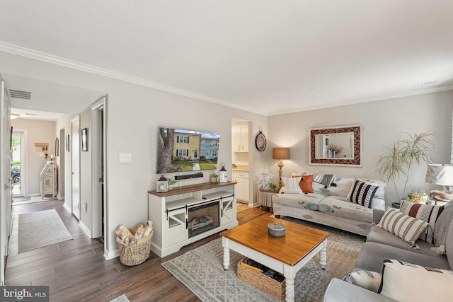 living room featuring dark wood-style flooring, crown molding, and baseboards