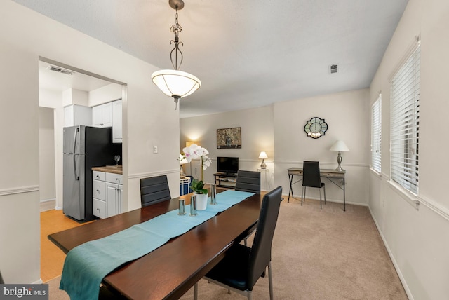 dining space with an office area, baseboards, and light colored carpet