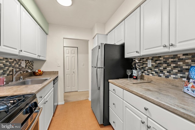 kitchen featuring a sink, white cabinets, backsplash, and stainless steel appliances