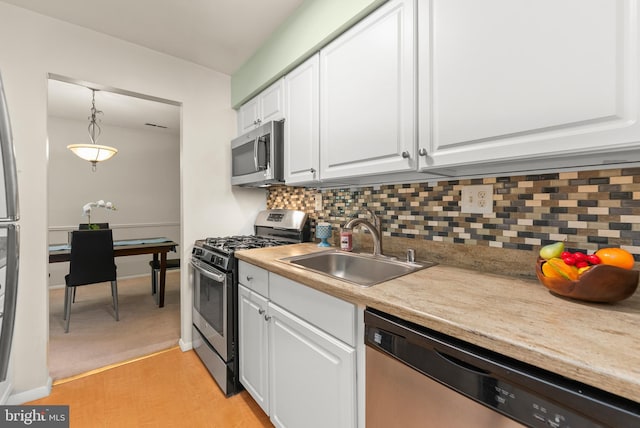 kitchen featuring appliances with stainless steel finishes, a sink, white cabinets, and tasteful backsplash