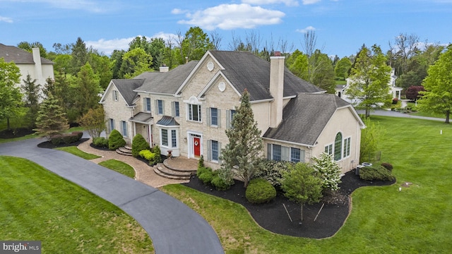 view of front of home featuring a chimney, a front yard, and view of wooded area