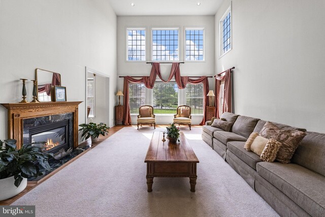 living room featuring a high ceiling, a fireplace, and carpet