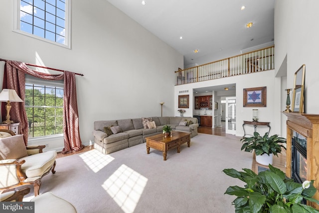 living room with a high ceiling, baseboards, carpet floors, and a premium fireplace