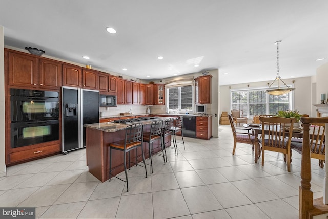kitchen with black appliances, a breakfast bar area, recessed lighting, pendant lighting, and a kitchen island