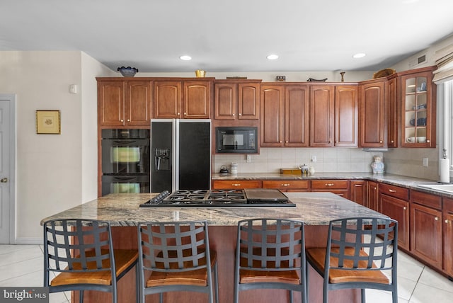 kitchen featuring black appliances, light tile patterned floors, a breakfast bar, and recessed lighting