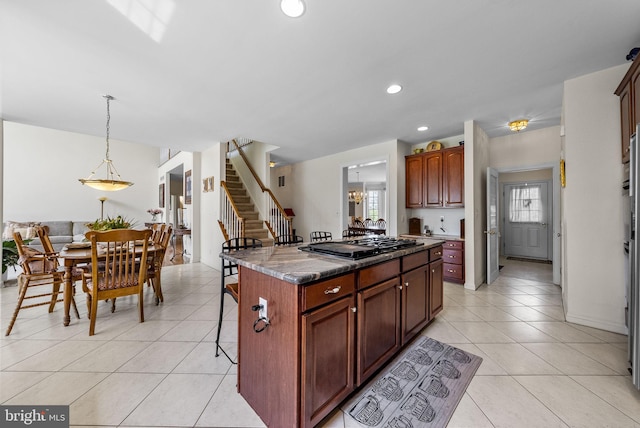 kitchen featuring black gas cooktop, a breakfast bar area, light tile patterned flooring, a center island, and recessed lighting