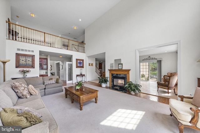 carpeted living area with a high ceiling and a high end fireplace