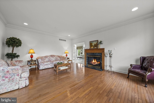living room featuring wood-type flooring, a fireplace, ornamental molding, recessed lighting, and baseboards