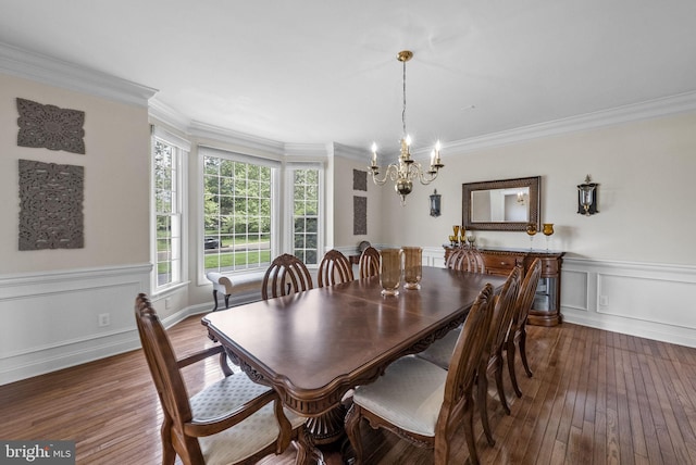 dining space featuring a chandelier, wood-type flooring, crown molding, and a wainscoted wall