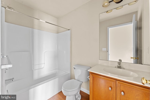 bathroom with vanity, shower / bath combination, toilet, wood finished floors, and baseboards