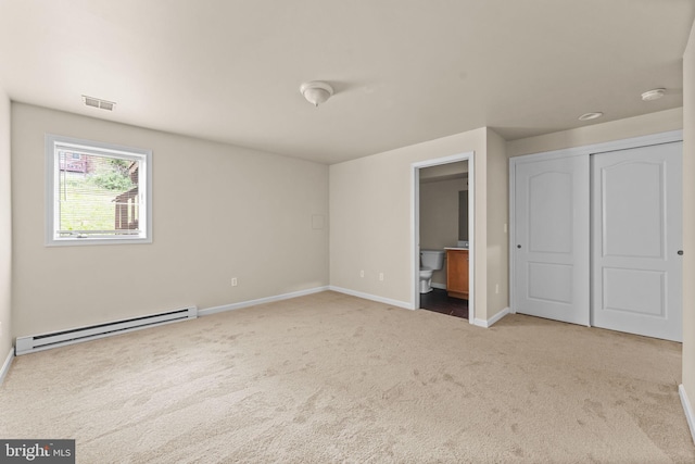 unfurnished bedroom featuring a baseboard radiator, carpet, baseboards, a closet, and ensuite bathroom