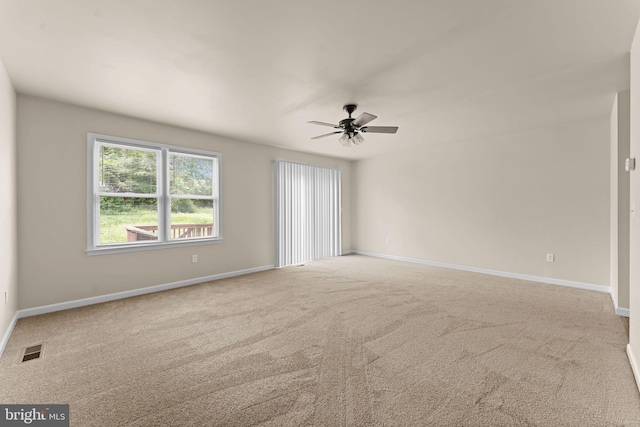 carpeted spare room featuring ceiling fan and baseboards