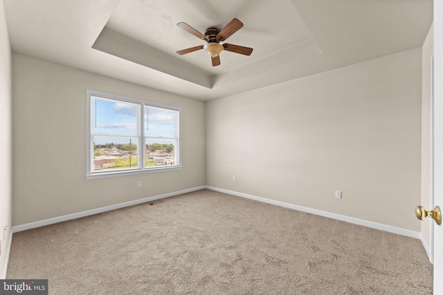 spare room with carpet floors, baseboards, ceiling fan, and a tray ceiling