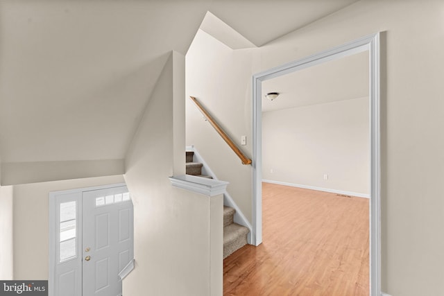 foyer featuring wood finished floors, stairs, and baseboards