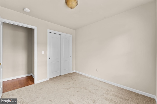 unfurnished bedroom featuring carpet floors, baseboards, and a closet