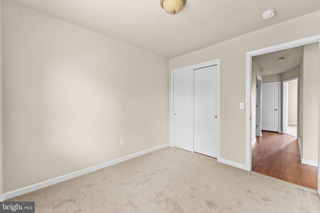 unfurnished bedroom featuring carpet, baseboards, and a closet
