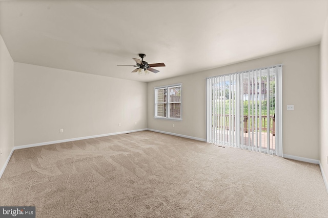 carpeted spare room with a ceiling fan and baseboards