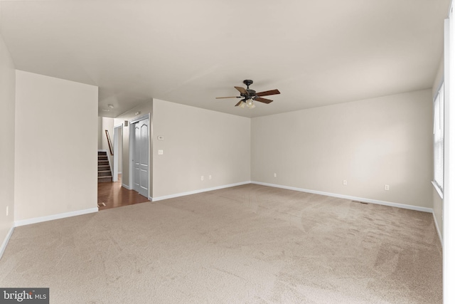 carpeted empty room featuring a ceiling fan and baseboards